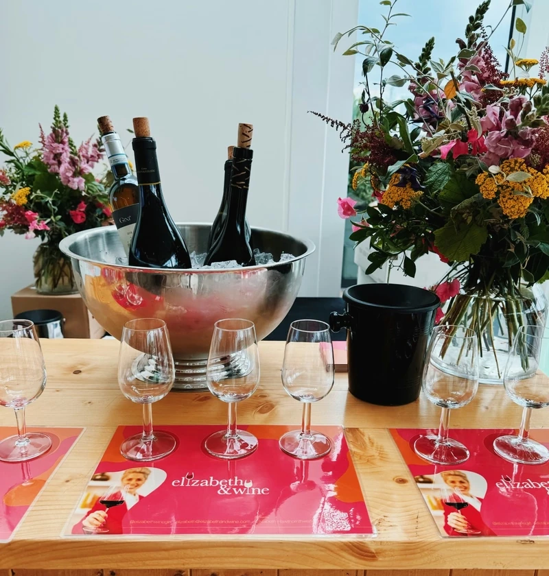 Wine bottles chilling in an ice bowl beside tasting glasses, flowers and Elizabeth & Wine mats
